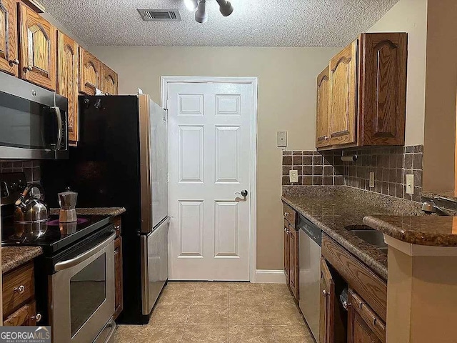 kitchen with stainless steel appliances, sink, a textured ceiling, and light tile patterned flooring