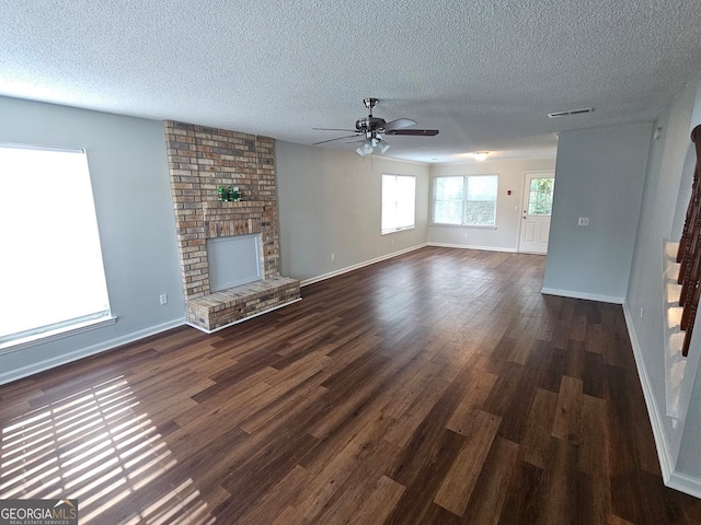 unfurnished living room with ceiling fan, a fireplace, dark hardwood / wood-style floors, and a textured ceiling