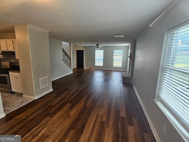 unfurnished living room with a fireplace, dark hardwood / wood-style flooring, ceiling fan, and a textured ceiling