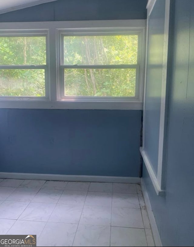 unfurnished room featuring lofted ceiling and light tile patterned floors