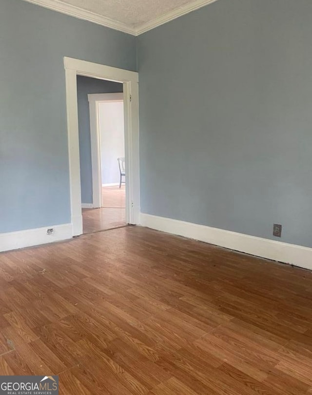 empty room featuring hardwood / wood-style floors and crown molding