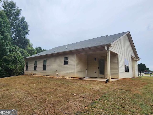 rear view of property featuring a lawn and a patio area