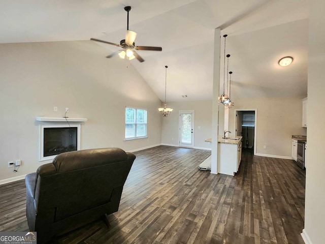 living room with dark wood-type flooring, ceiling fan with notable chandelier, and high vaulted ceiling