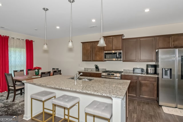 kitchen with an island with sink, hanging light fixtures, and stainless steel appliances