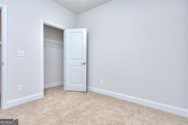 unfurnished bedroom with light carpet and a closet