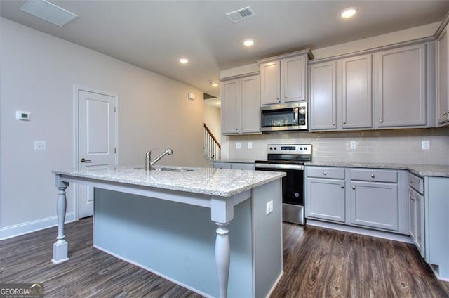 kitchen with a kitchen island with sink, appliances with stainless steel finishes, and dark hardwood / wood-style flooring