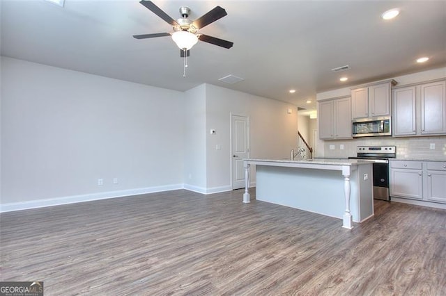 kitchen with appliances with stainless steel finishes, a center island with sink, ceiling fan, and gray cabinets