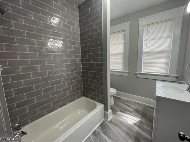 full bathroom featuring toilet, tiled shower / bath, vanity, a textured ceiling, and hardwood / wood-style flooring