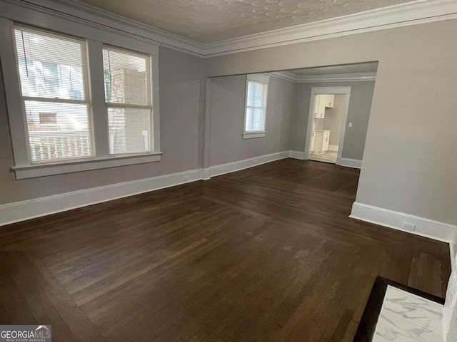 spare room featuring ornamental molding, a textured ceiling, a healthy amount of sunlight, and dark hardwood / wood-style flooring