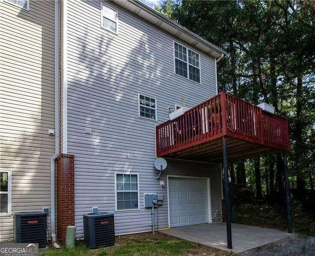 back of house with a garage, central air condition unit, and a wooden deck