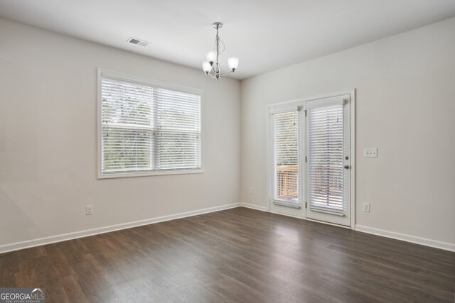 unfurnished room featuring dark wood-type flooring and a notable chandelier