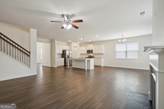 unfurnished living room featuring ceiling fan with notable chandelier and dark hardwood / wood-style flooring