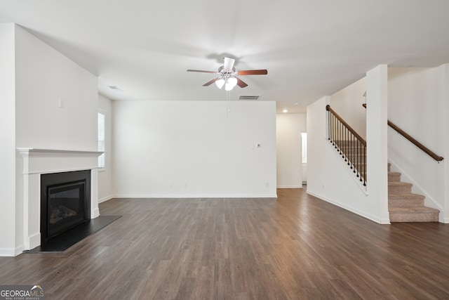 unfurnished living room with dark hardwood / wood-style flooring and ceiling fan