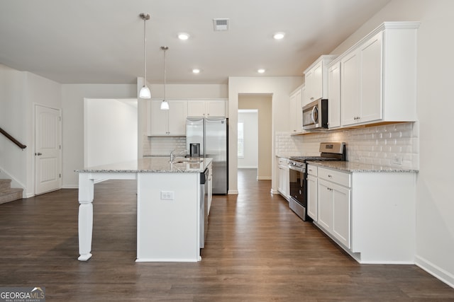 kitchen featuring stainless steel appliances, an island with sink, hanging light fixtures, dark wood-type flooring, and white cabinets