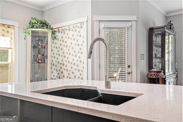 kitchen with sink, light stone counters, and ornamental molding