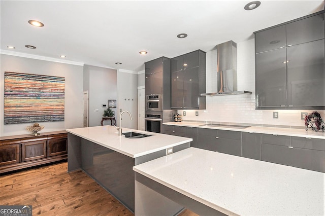 kitchen featuring sink, hardwood / wood-style floors, gray cabinetry, and wall chimney range hood