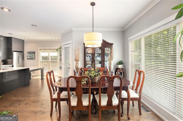 dining space featuring crown molding, light hardwood / wood-style floors, and sink