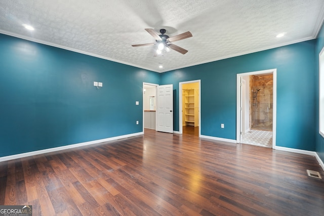 unfurnished bedroom featuring connected bathroom, ceiling fan, a closet, dark wood-type flooring, and a walk in closet