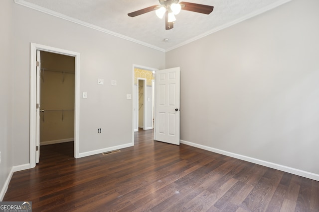 unfurnished bedroom featuring a closet, a spacious closet, ceiling fan, and dark hardwood / wood-style floors