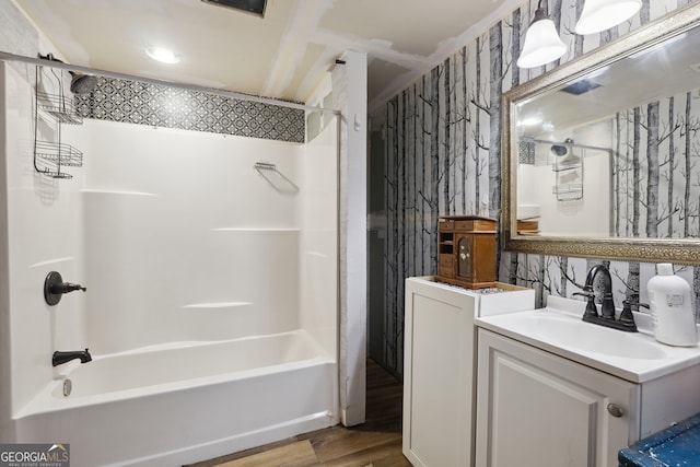 bathroom featuring washer / dryer, vanity, washtub / shower combination, and hardwood / wood-style flooring