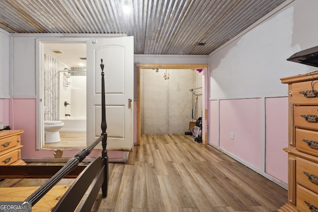 bedroom with light hardwood / wood-style floors and ensuite bath