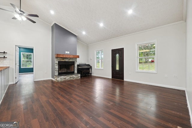 unfurnished living room featuring a wealth of natural light, ceiling fan, a stone fireplace, and dark hardwood / wood-style flooring