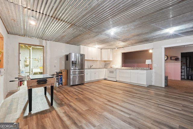 kitchen with stainless steel fridge, light hardwood / wood-style flooring, electric range, sink, and white cabinets