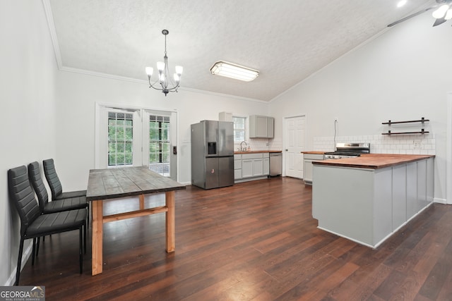 kitchen featuring stainless steel appliances, dark hardwood / wood-style flooring, wood counters, hanging light fixtures, and vaulted ceiling