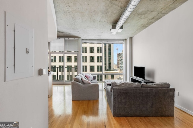 living room featuring electric panel, light hardwood / wood-style flooring, and a wall of windows