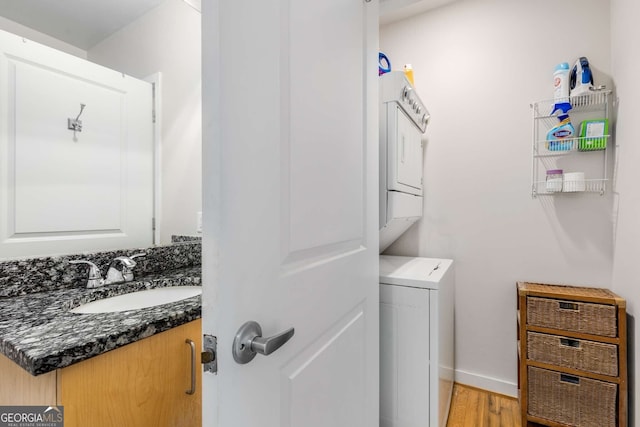 washroom with light wood-type flooring, sink, and stacked washer / dryer