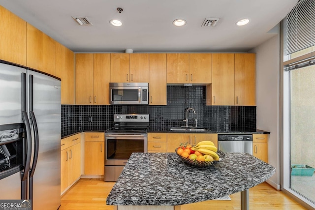 kitchen featuring light hardwood / wood-style flooring, appliances with stainless steel finishes, backsplash, and sink