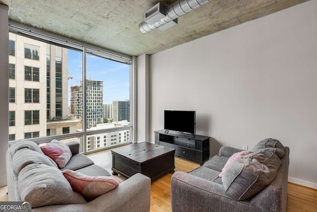 living room with a wall of windows and light hardwood / wood-style floors