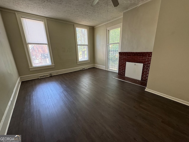 unfurnished living room featuring ceiling fan, a fireplace, dark hardwood / wood-style flooring, and a textured ceiling