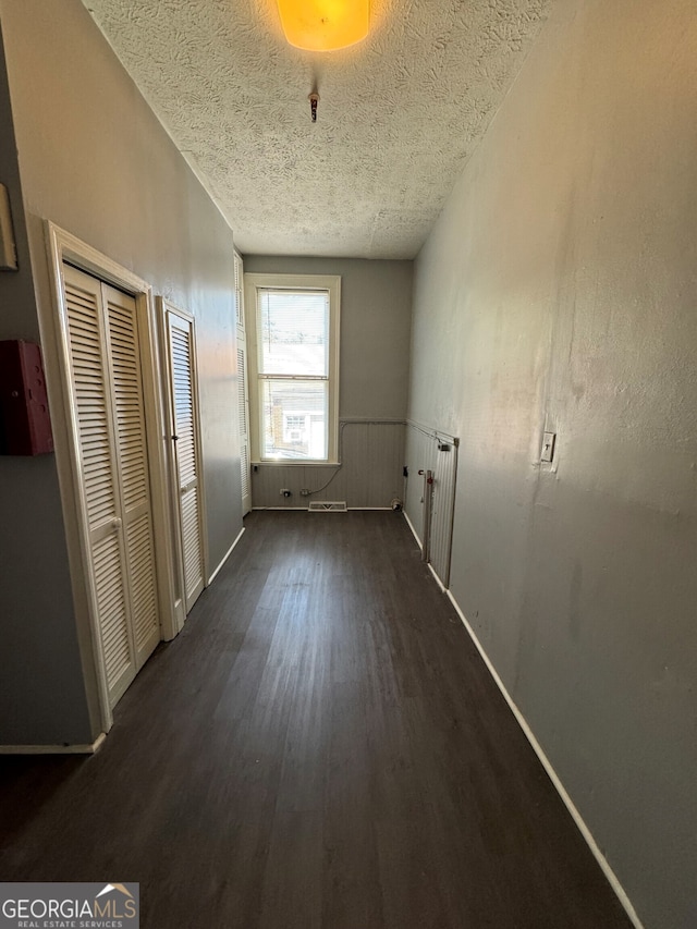 hallway with dark wood-type flooring, radiator, and a textured ceiling