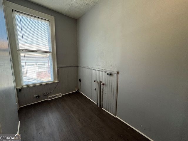 spare room featuring wood walls and dark hardwood / wood-style flooring