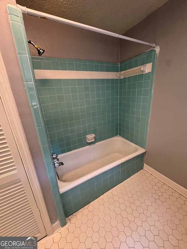 bathroom with tiled shower / bath and a textured ceiling