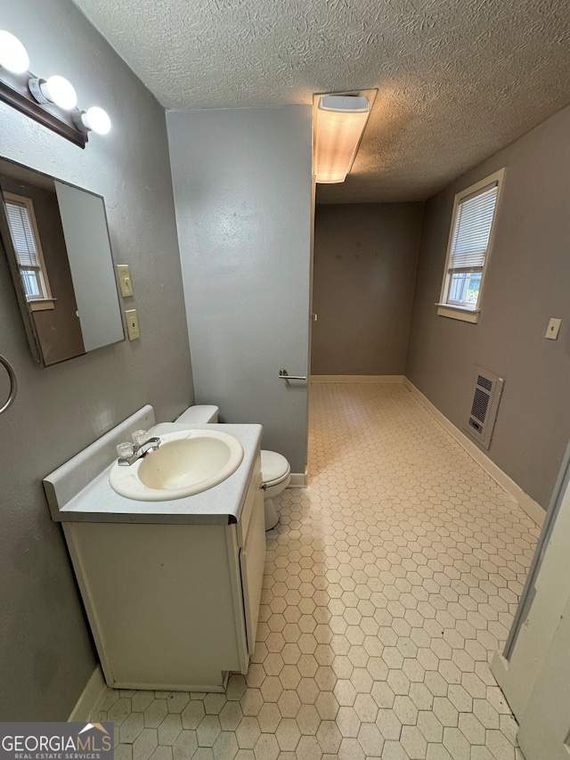 bathroom featuring a textured ceiling, vanity, toilet, and heating unit