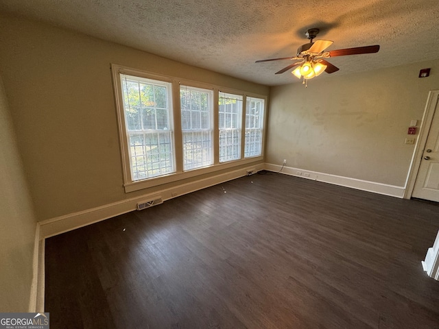 spare room featuring dark wood-type flooring, a textured ceiling, and ceiling fan