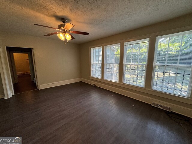 empty room with a textured ceiling, ceiling fan, and dark hardwood / wood-style floors