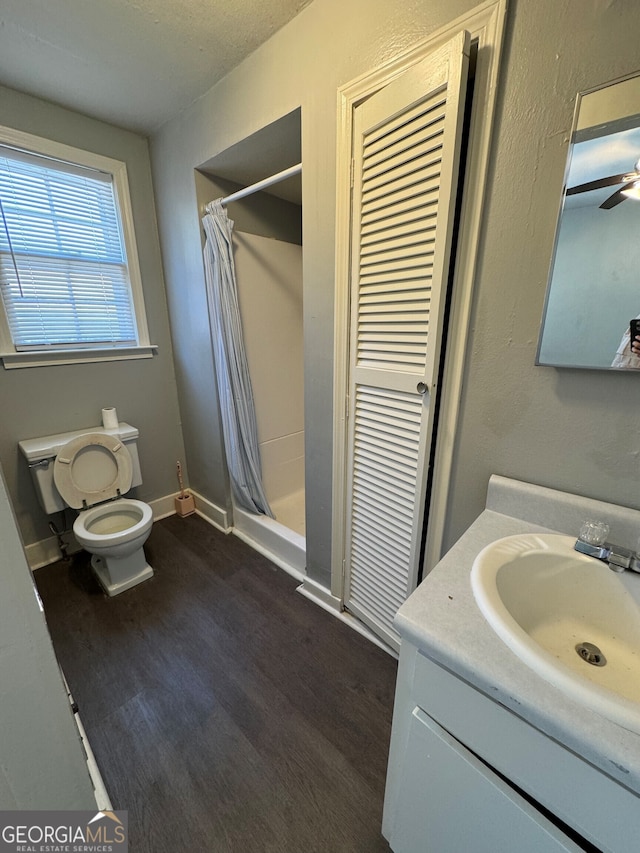 bathroom featuring vanity, a shower with shower curtain, wood-type flooring, toilet, and ceiling fan