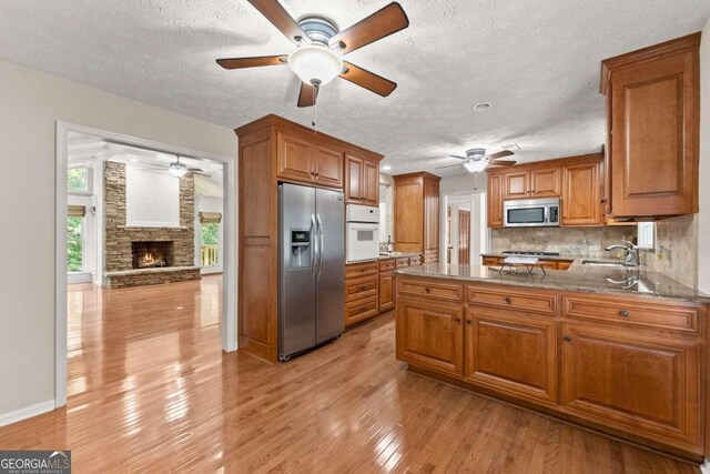5775 Lakeshore Dr, Buford, GA 30518 - kitchen featuring stainless steel appliances, a ceiling fan, brown cabinetry, a sink, and a textured ceiling