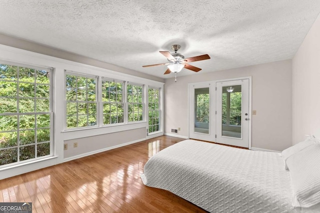 5775 Lakeshore Dr, Buford, GA 30518 - bedroom featuring access to exterior, baseboards, hardwood / wood-style flooring, a textured ceiling, and ceiling fan