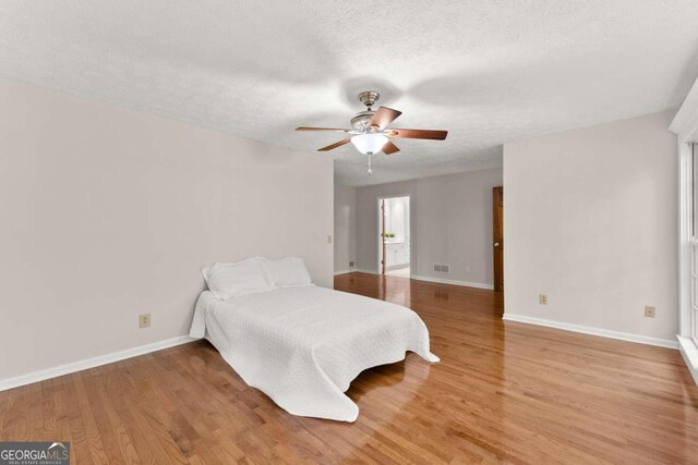 5775 Lakeshore Dr, Buford, GA 30518 - bedroom featuring baseboards, light wood-type flooring, a textured ceiling, and ceiling fan