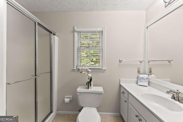 bathroom featuring tile patterned flooring, walk in shower, toilet, vanity, and a textured ceiling