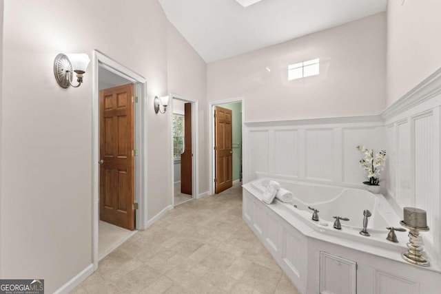 bathroom featuring a bath and high vaulted ceiling