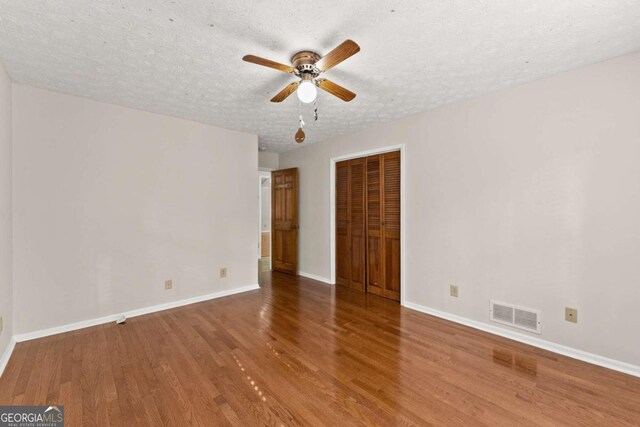 empty room featuring a textured ceiling, hardwood / wood-style flooring, and ceiling fan