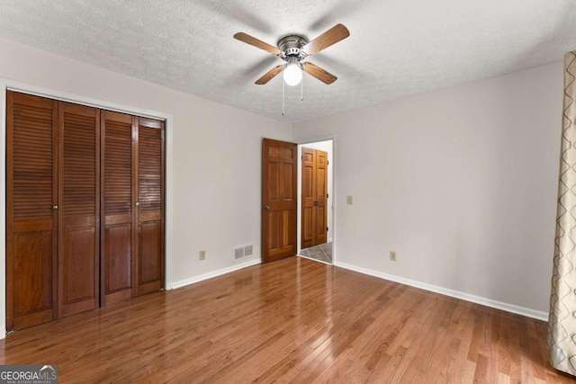 5775 Lakeshore Dr, Buford, GA 30518 - unfurnished bedroom with baseboards, light wood finished floors, a closet, a textured ceiling, and ceiling fan