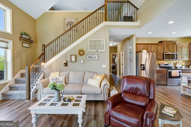 living room with washer / clothes dryer, a high ceiling, and hardwood / wood-style flooring