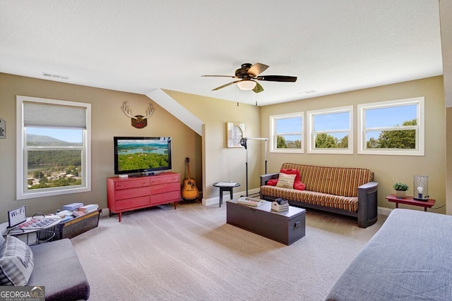 living room with light colored carpet, plenty of natural light, ceiling fan, and a textured ceiling