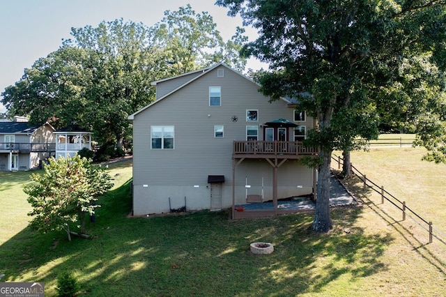 back of house with a yard, an outdoor fire pit, and a deck